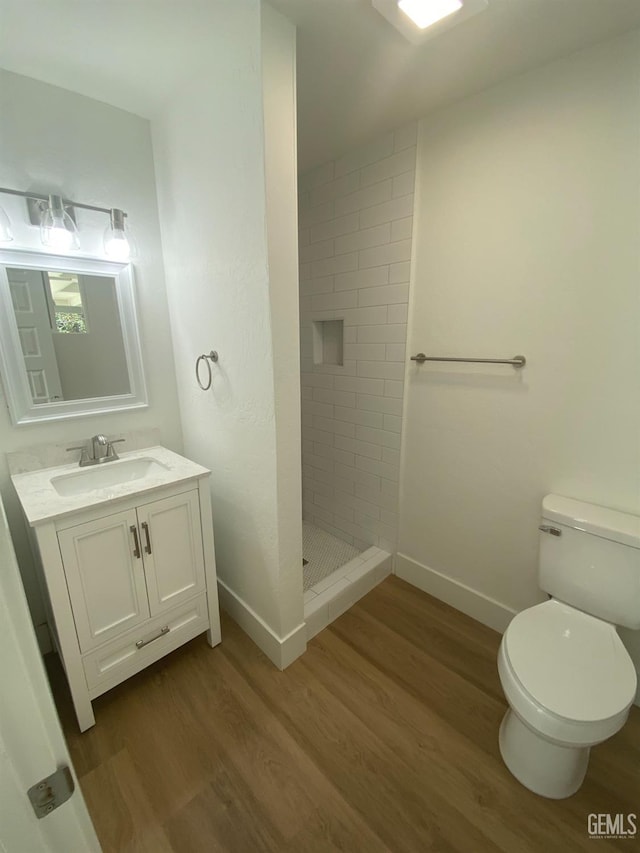 351 Adams St, Wasco, CA 93280 - full bathroom featuring wood finished floors, toilet, baseboards, and tiled shower