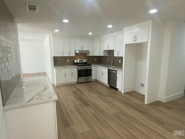 351 Adams St, Wasco, CA 93280 - kitchen with stainless steel appliances, a sink, under cabinet range hood, light wood-style flooring, and white cabinets