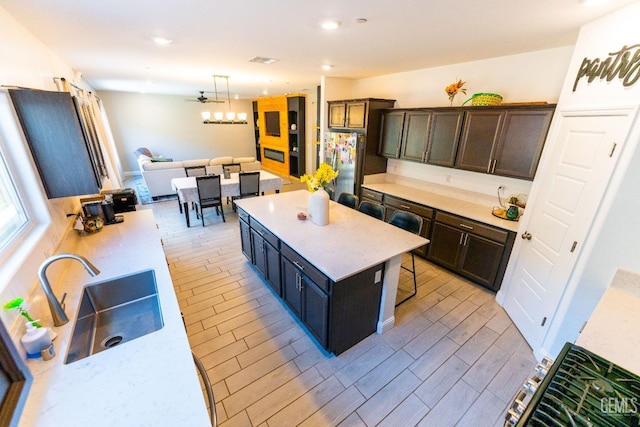 kitchen with stainless steel fridge, sink, a center island, hanging light fixtures, and a breakfast bar area