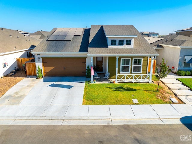 view of front of house featuring a porch, a garage, a front yard, and solar panels