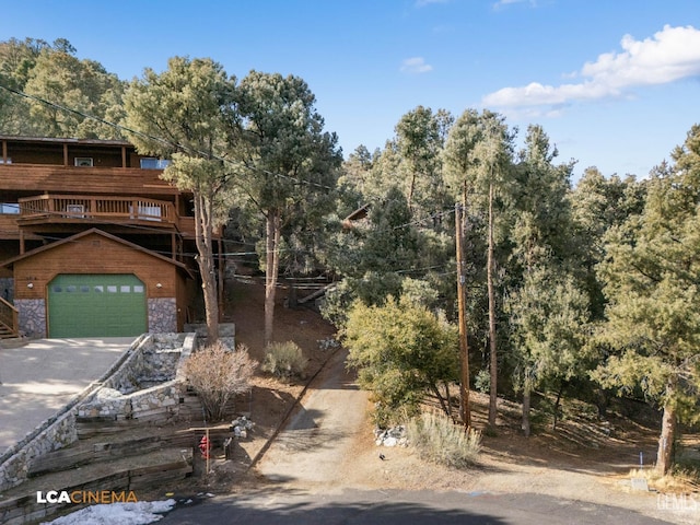 view of front of home with a wooden deck, stone siding, an attached garage, and driveway