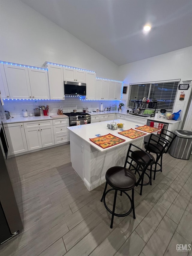 kitchen with white cabinetry, a center island, stainless steel appliances, backsplash, and a breakfast bar area