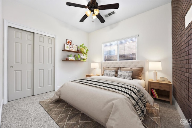 carpeted bedroom featuring brick wall, ceiling fan, and a closet