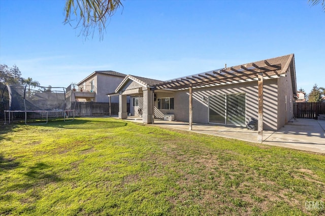 rear view of house with a patio, a yard, a pergola, and a trampoline