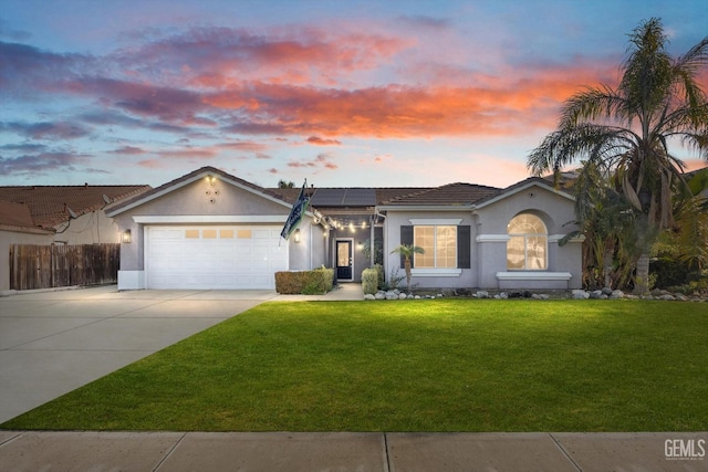 single story home with a garage, a yard, and solar panels