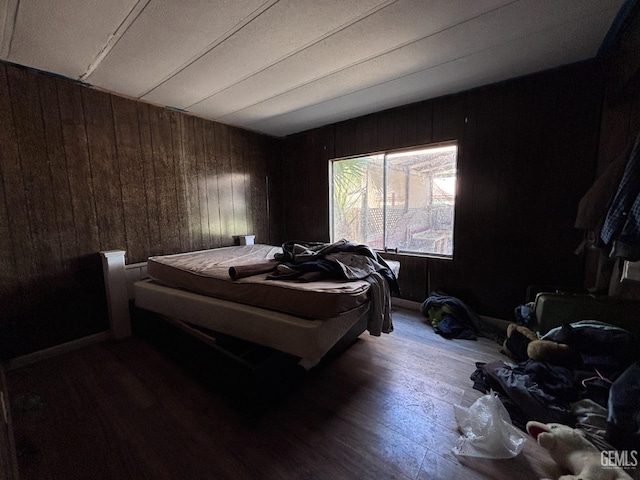 bedroom with wood-type flooring and wooden walls