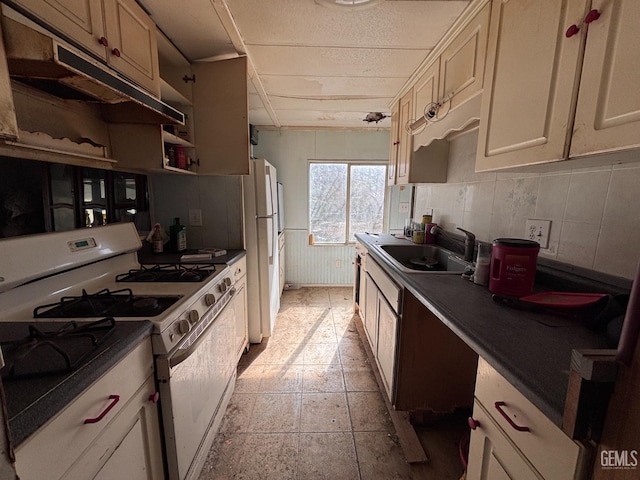 kitchen featuring tasteful backsplash, sink, white appliances, and cream cabinets