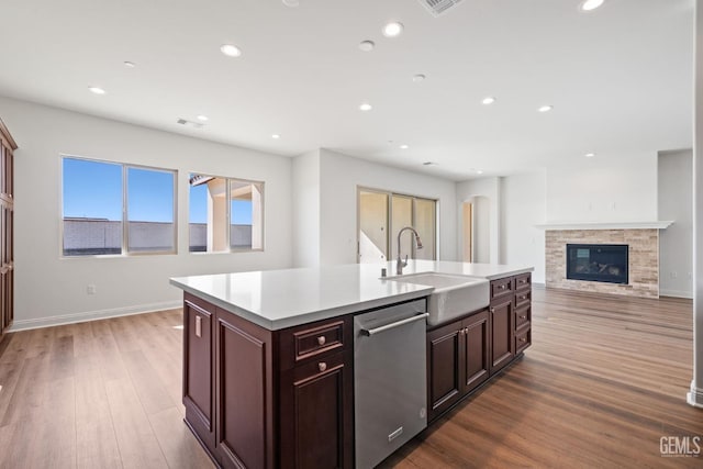 kitchen with sink, hardwood / wood-style floors, stainless steel dishwasher, and a kitchen island with sink