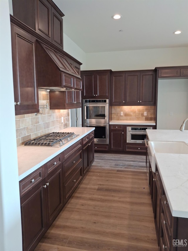 kitchen featuring decorative backsplash, sink, dark brown cabinetry, stainless steel appliances, and dark hardwood / wood-style flooring