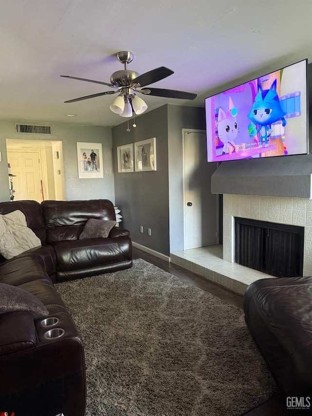 living room with baseboards, visible vents, ceiling fan, a tile fireplace, and carpet floors