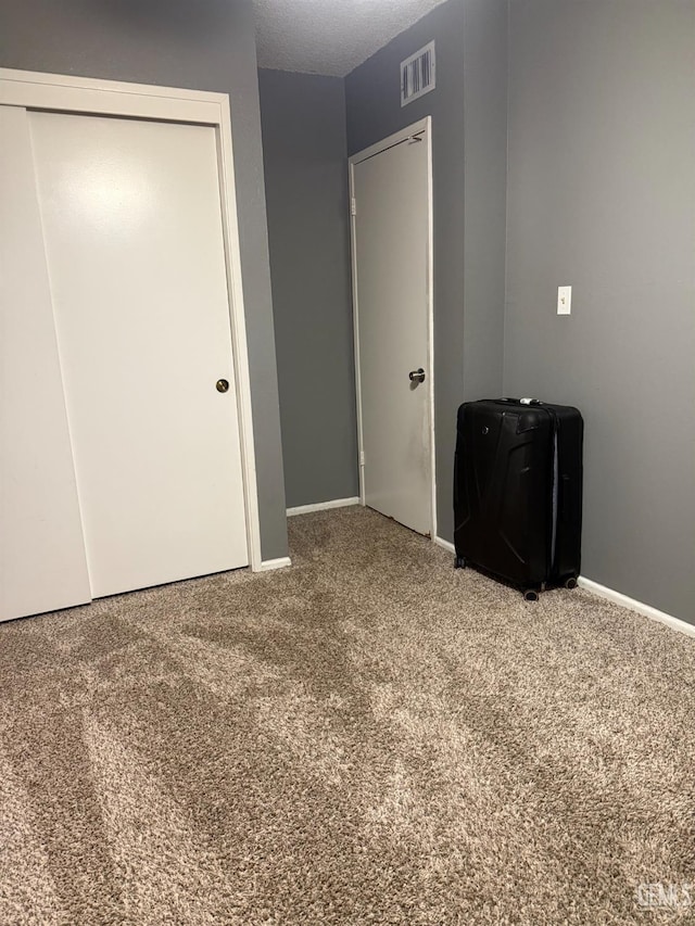 unfurnished bedroom featuring visible vents, baseboards, carpet, and a closet