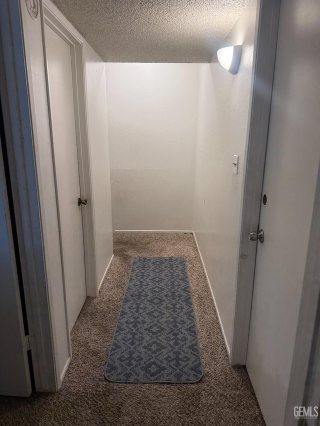 hallway with carpet, a textured ceiling, and baseboards