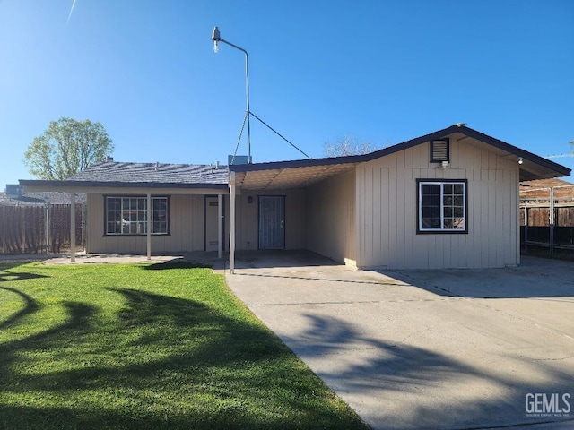 single story home featuring driveway, a front lawn, fence, and an attached carport