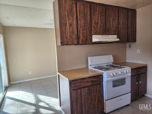 kitchen with light tile patterned floors, a textured ceiling, white range with gas stovetop, under cabinet range hood, and dark brown cabinets