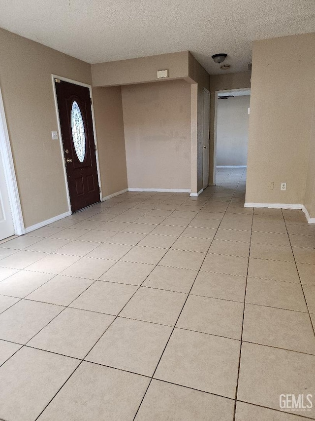 foyer with light tile patterned flooring, a textured ceiling, and baseboards