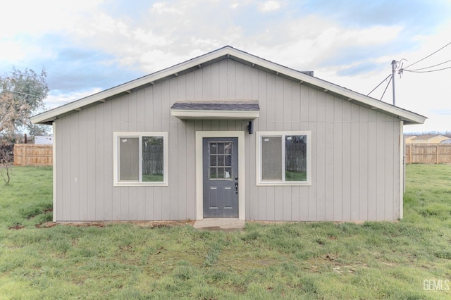 view of front facade featuring a front yard, fence, and an outdoor structure