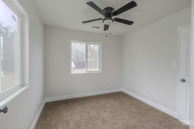 carpeted empty room with visible vents, baseboards, and a ceiling fan