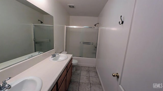 full bathroom featuring tile patterned flooring, vanity, toilet, and bath / shower combo with glass door