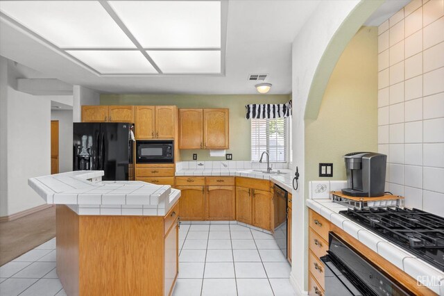 7601 Live Oak Way, Bakersfield, CA 93308 - kitchen with black appliances, a sink, tile counters, and arched walkways