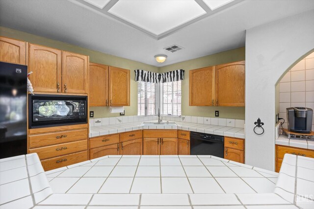 7601 Live Oak Way, Bakersfield, CA 93308 - kitchen with black appliances, a sink, tile counters, and arched walkways