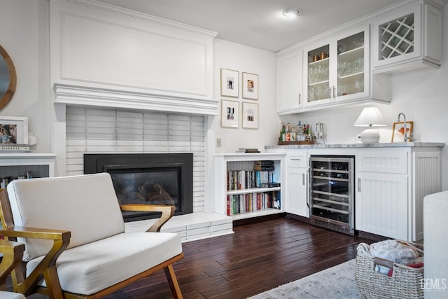 sitting room with wine cooler, dark hardwood / wood-style flooring, a fireplace, and indoor bar