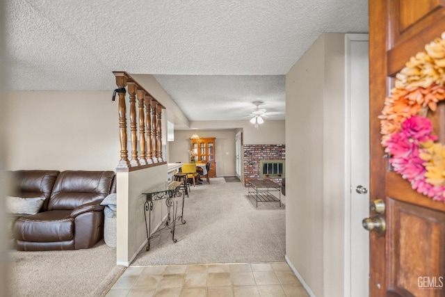 interior space with ceiling fan, light colored carpet, a textured ceiling, and a brick fireplace