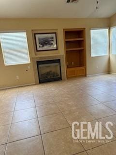 10011 Grand View Summit Dr, Bakersfield, CA 93311 - unfurnished living room featuring built in features, a fireplace, light tile patterned floors, and healthy amount of natural light