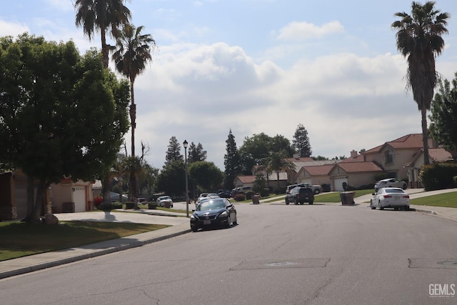 view of street featuring a residential view, sidewalks, curbs, and street lighting