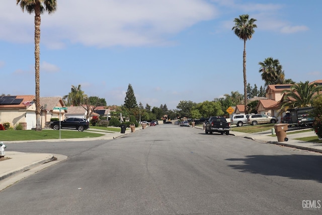 view of road with a residential view, traffic signs, sidewalks, and curbs
