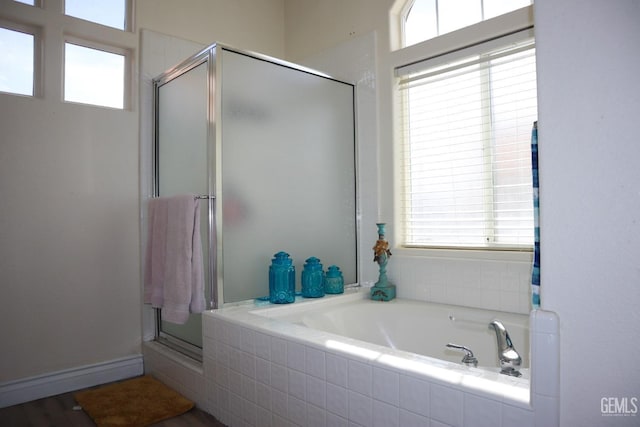 bathroom featuring plenty of natural light, a shower stall, and a garden tub