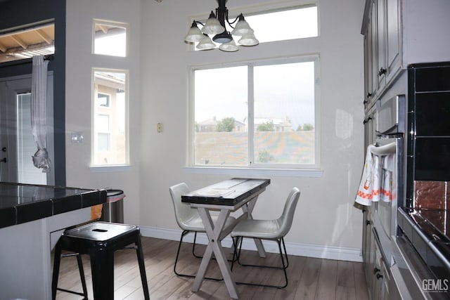 dining space with an inviting chandelier, baseboards, and wood finished floors