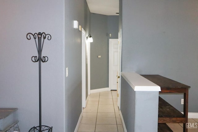 hallway with light tile patterned floors and baseboards