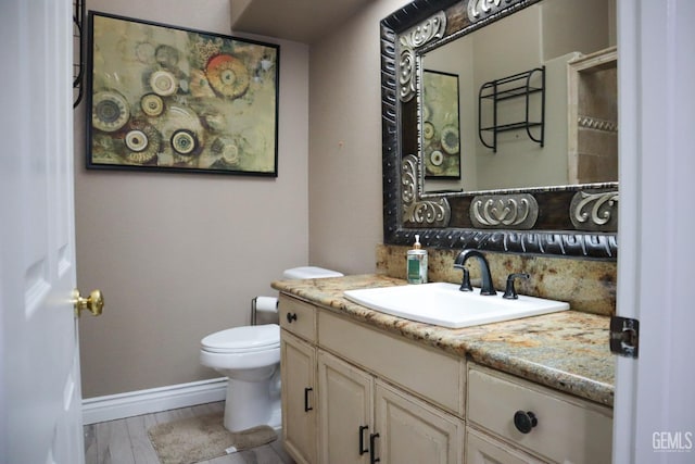 bathroom featuring baseboards, toilet, decorative backsplash, wood finished floors, and vanity