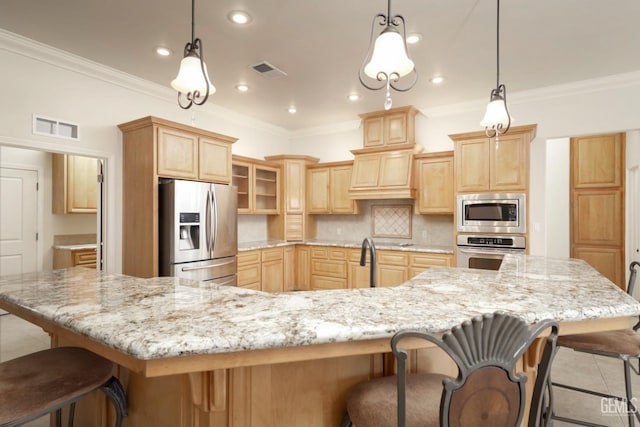 kitchen with decorative backsplash, appliances with stainless steel finishes, light brown cabinets, hanging light fixtures, and a breakfast bar area