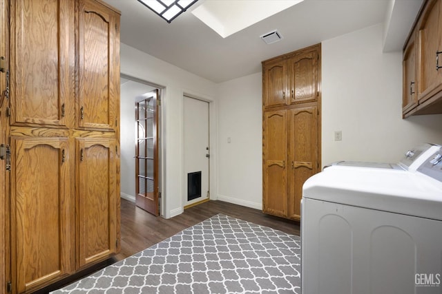 laundry area featuring washing machine and dryer, dark hardwood / wood-style flooring, and cabinets