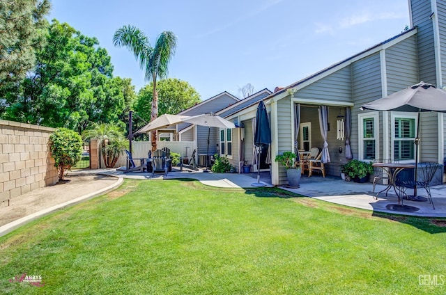 back of house featuring fence, a patio area, and a yard