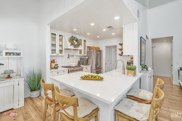 kitchen featuring light wood finished floors, decorative backsplash, visible vents, and high quality appliances