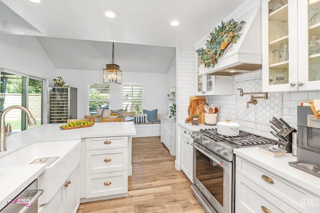 kitchen with stainless steel appliances, light wood-style flooring, a sink, custom exhaust hood, and lofted ceiling
