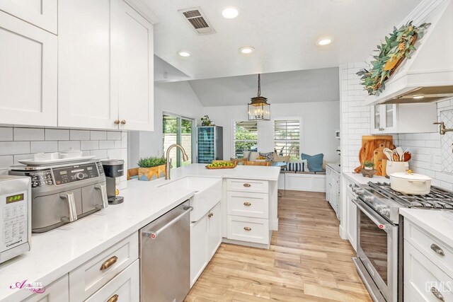 kitchen featuring custom exhaust hood, tasteful backsplash, a peninsula, appliances with stainless steel finishes, and visible vents