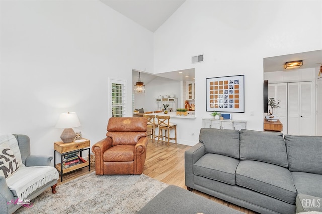 living area featuring wood finished floors, visible vents, and high vaulted ceiling