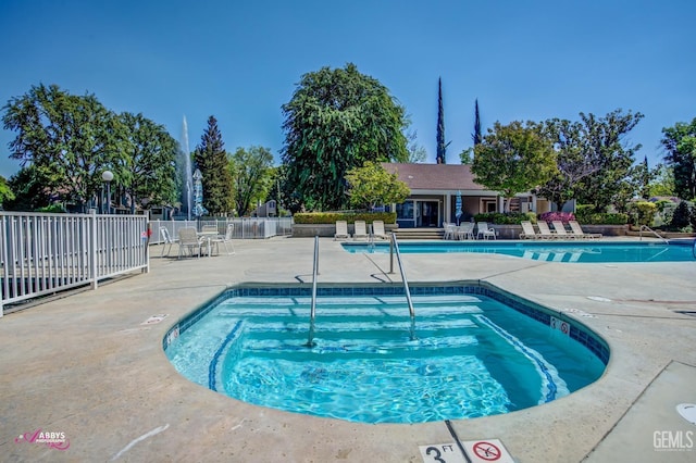 pool featuring fence, a community hot tub, and a patio