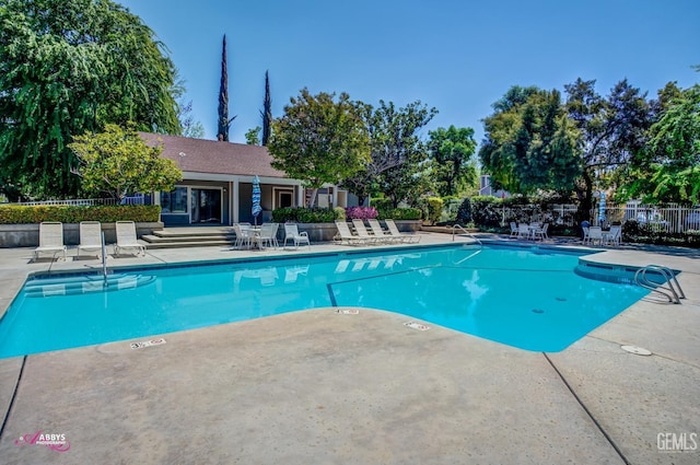 community pool with a patio area and fence