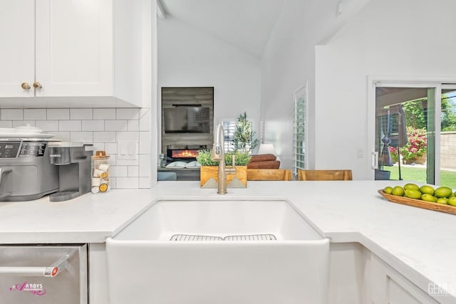 kitchen with lofted ceiling, light countertops, a sink, decorative backsplash, and white cabinetry