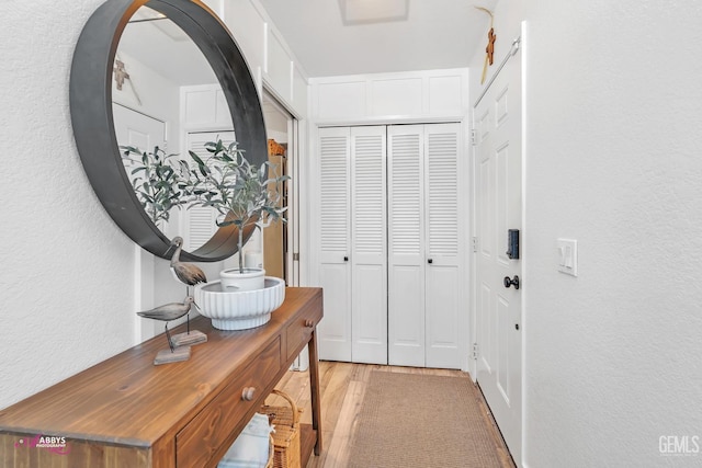 hallway with light wood-style floors and a textured wall