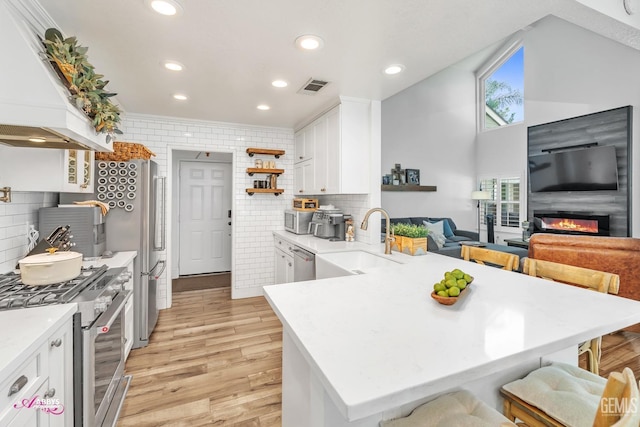 kitchen featuring stainless steel appliances, open shelves, visible vents, a sink, and premium range hood