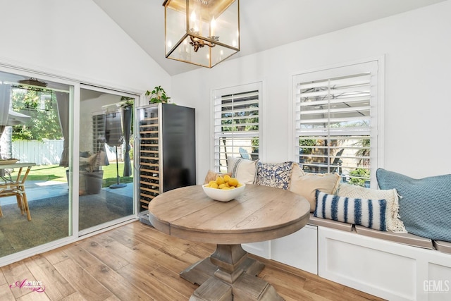 dining space with an inviting chandelier, a healthy amount of sunlight, wine cooler, and light wood-style flooring