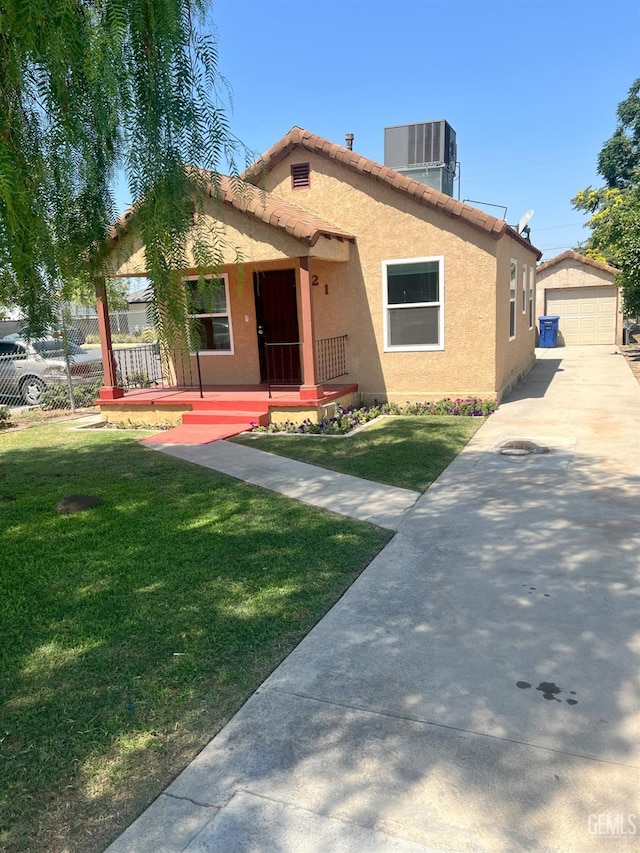 view of front facade with an outbuilding, stucco siding, central air condition unit, covered porch, and a front lawn