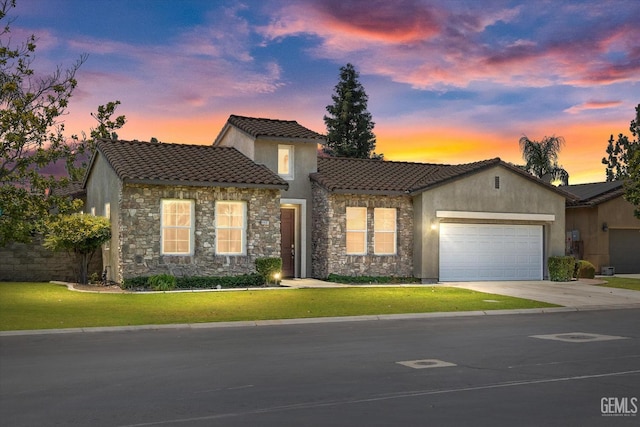 mediterranean / spanish home featuring a garage and a yard