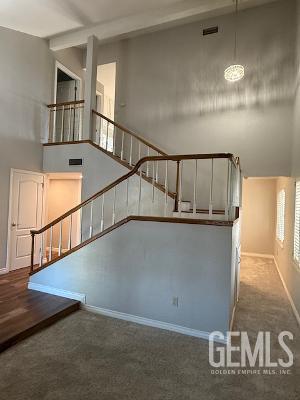 staircase featuring carpet, a high ceiling, and a notable chandelier