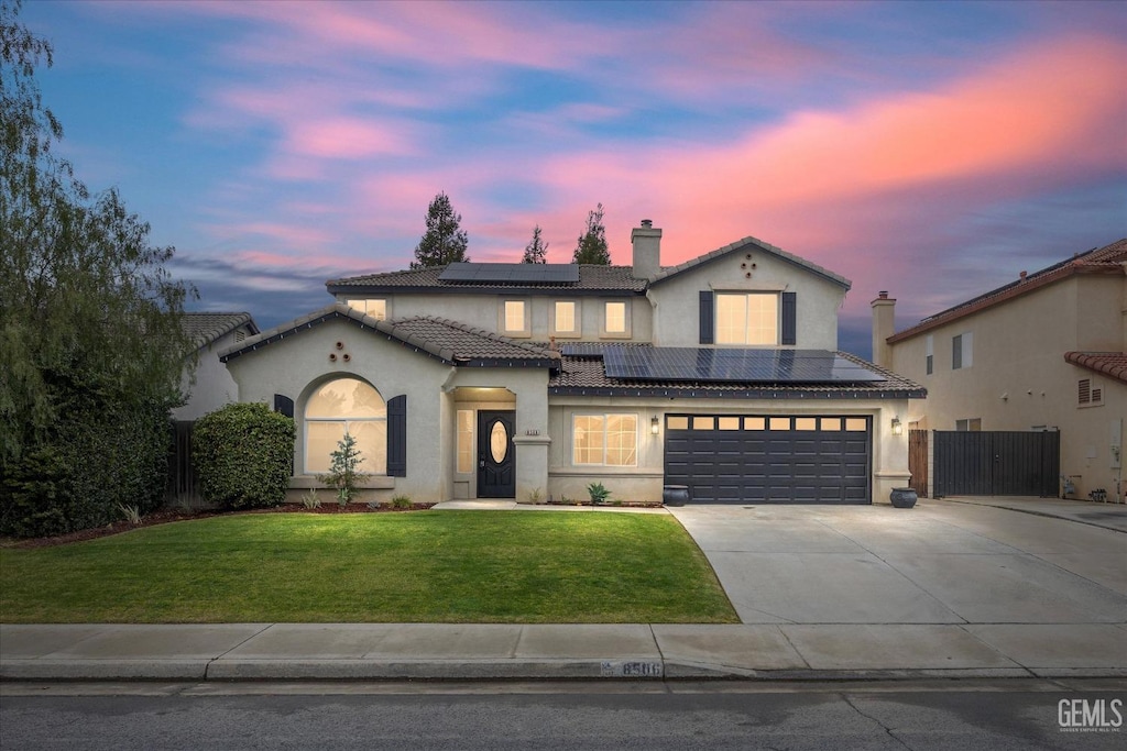 view of front of home with a garage, a yard, and solar panels